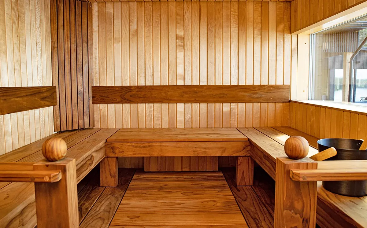 Interior da sauna com bancos de madeira e janela para o lago, Pistohiekka, Puumala